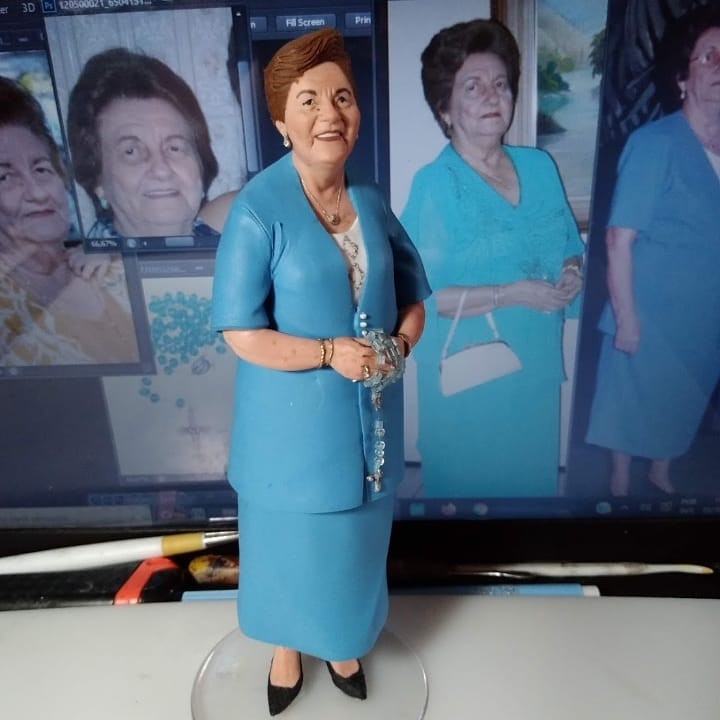 Miniatura detalhada de senhora de vestido azul com colar, cercada por fotos da pessoa real